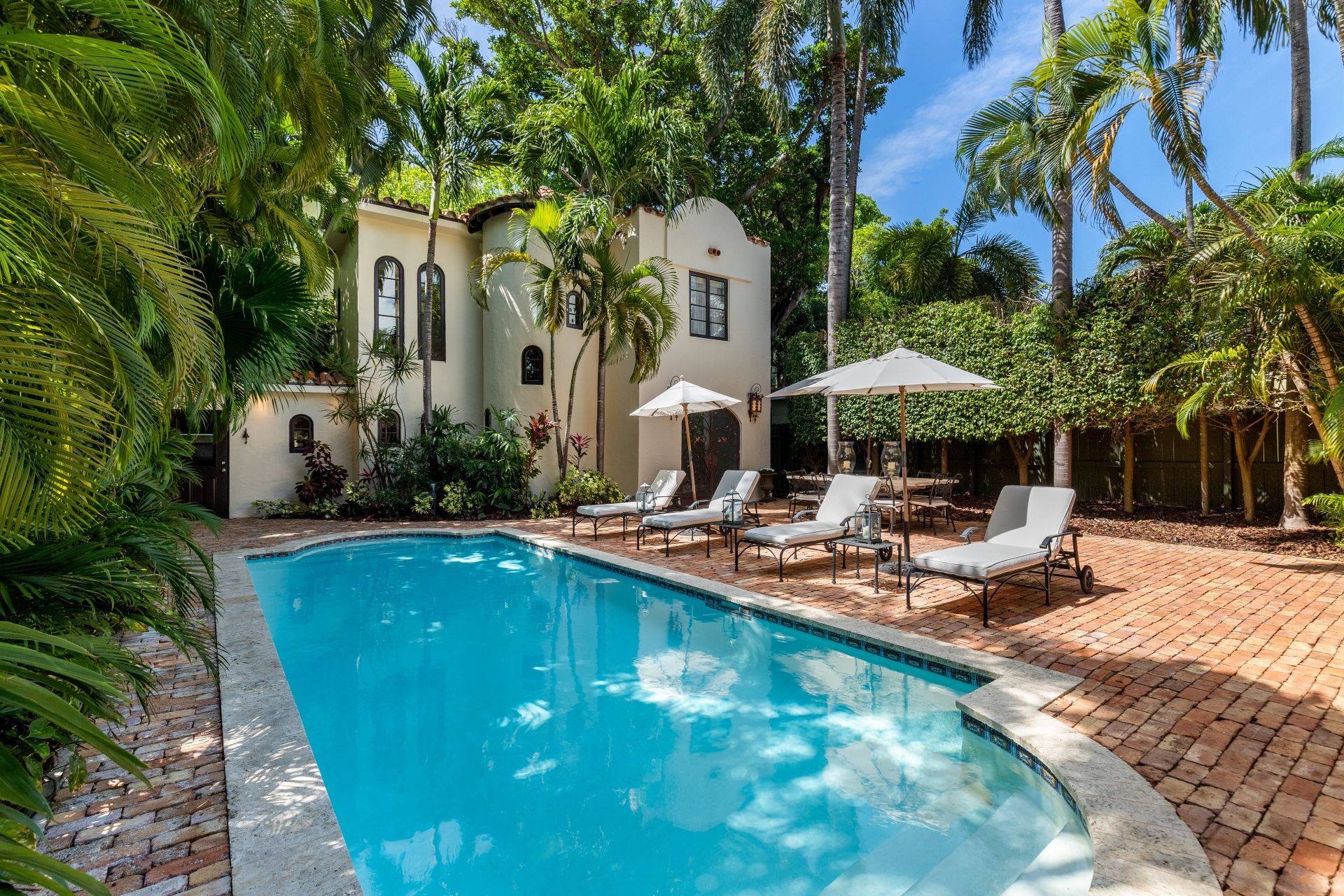 Florida, USA. January Backyard of a modern house with swimming pool, artificial grass, stone path, trees, chairs and an umbrella.
