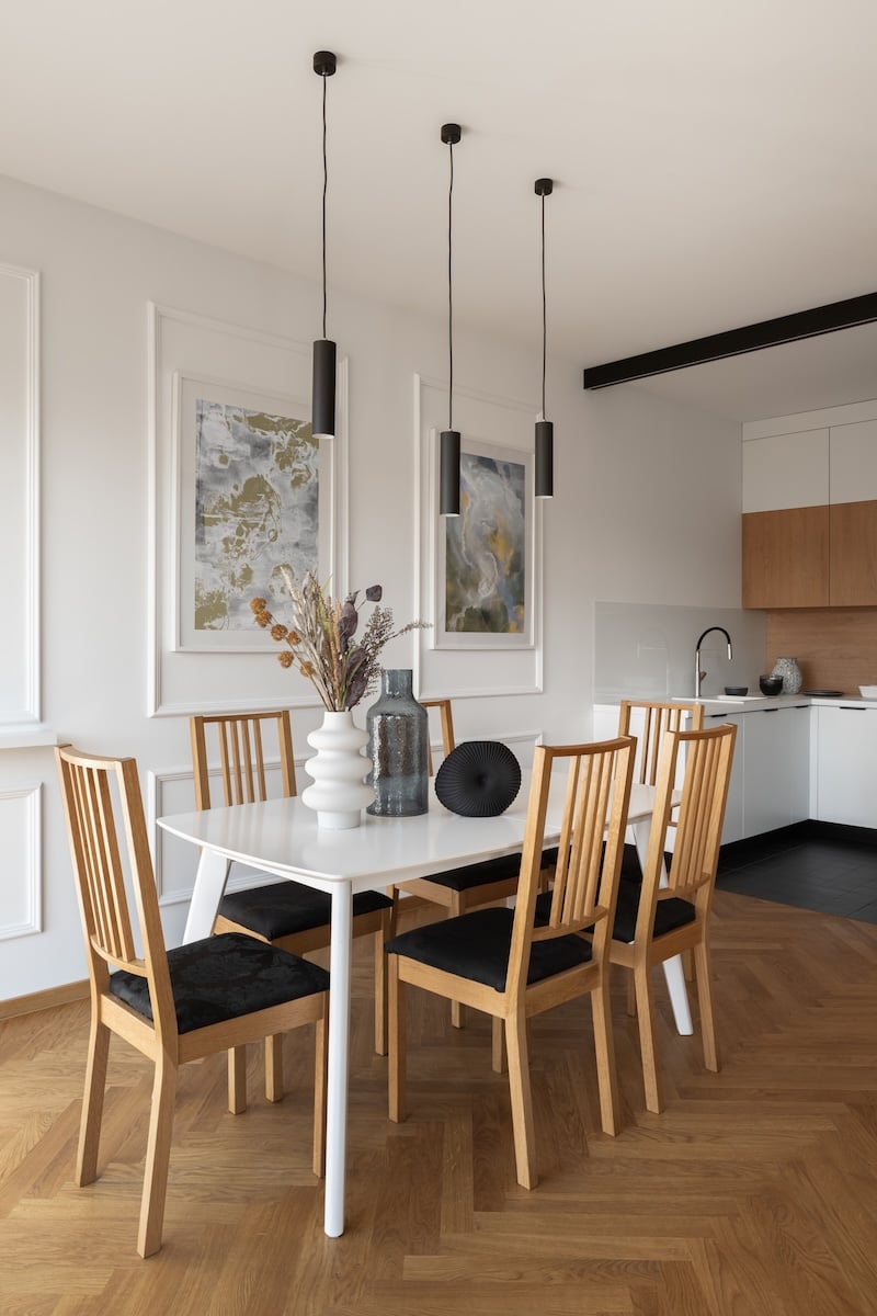 Simple dining table with six wooden chairs and stylish decorations next to modern kitchen (1)
