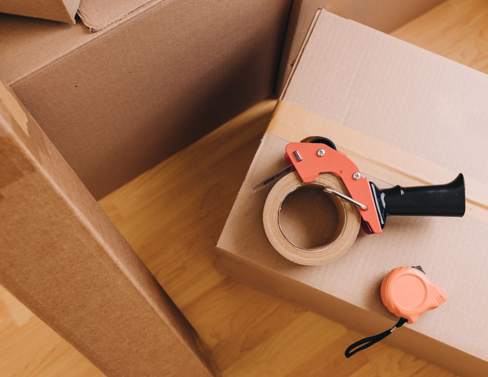 Moving boxes stacked neatly with a tape measure and notepad for planning rightsizing costs