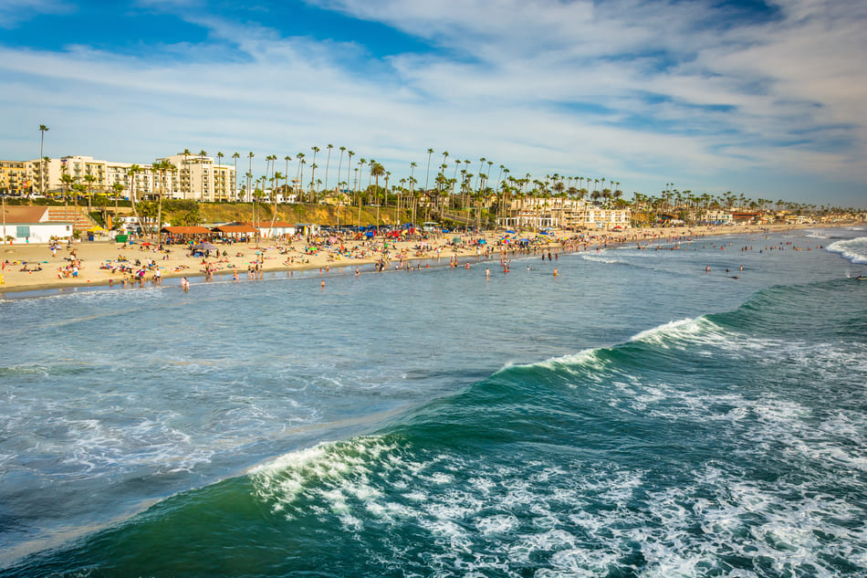View of the beach and waves in the Pacific Ocean from the pier in Oceanside, California.