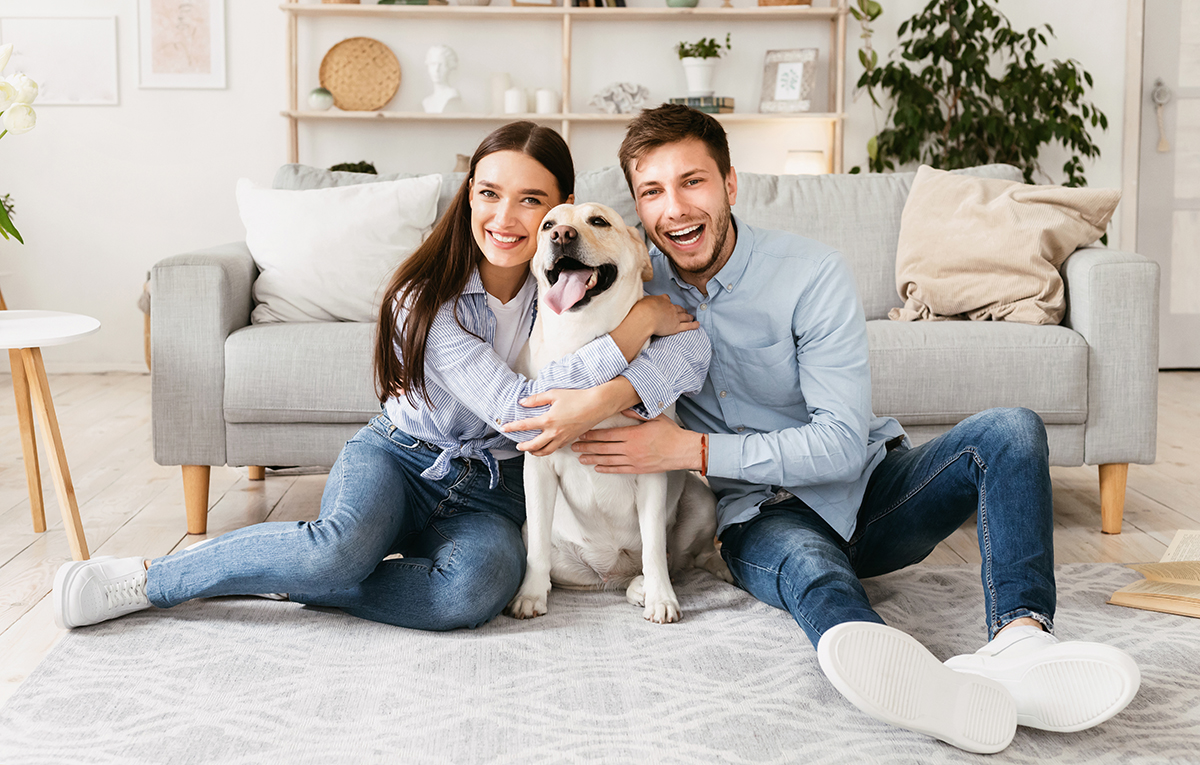 Young happy couple with dog sitting on floor