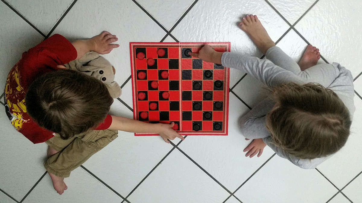 twins-playing-a-game-of-checkers-V9SQRLB