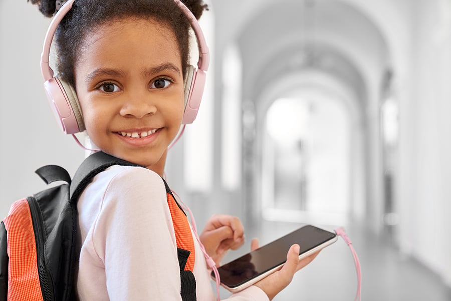 Child with school backpack and headphones posing.