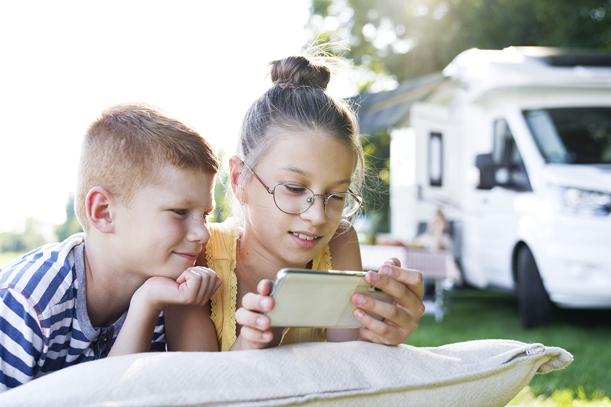 Children with mobile phone on camping holiday