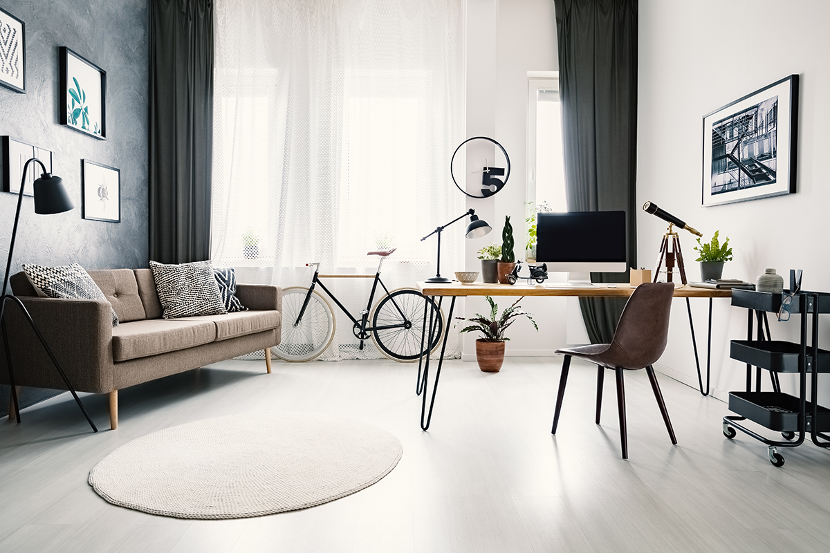 Modern home office interior with a big window, sofa, bike and de