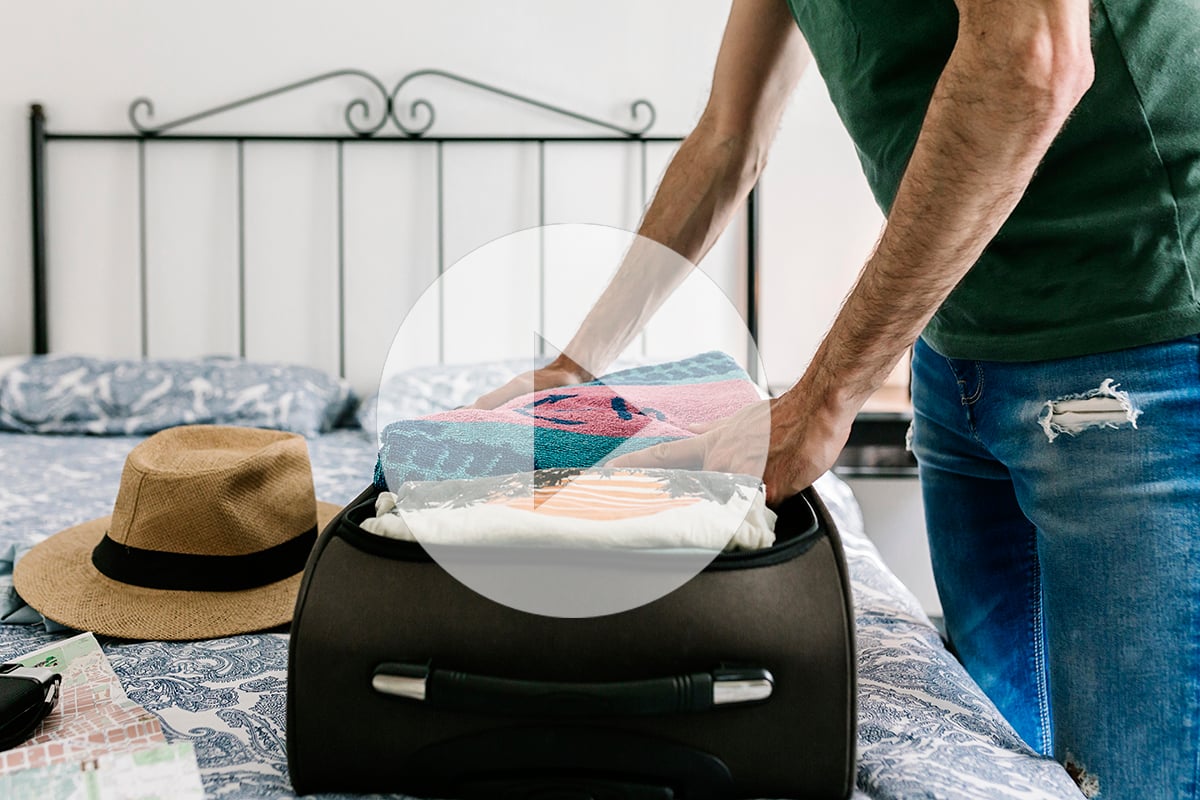 Young hispanic man unpacking his suitcase in an apartment. Trave