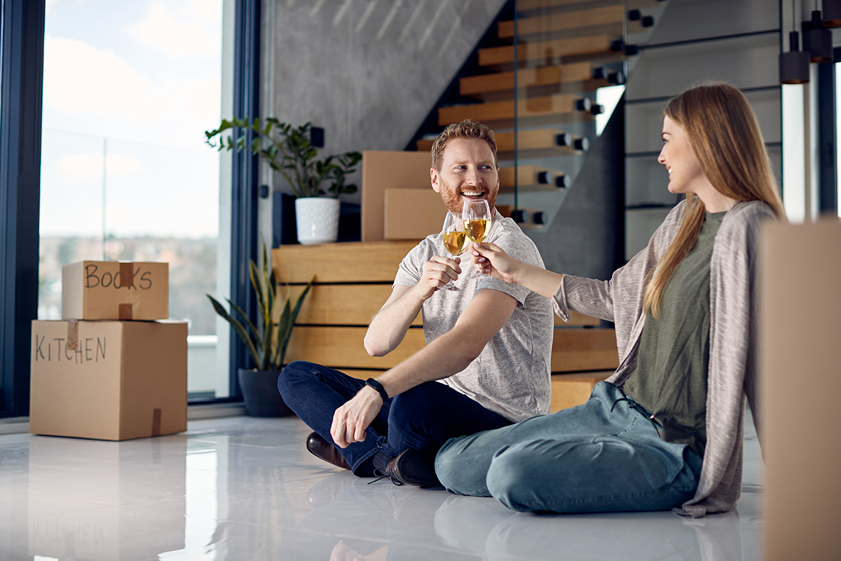 Happy couple toasting with wine after buying their first home.