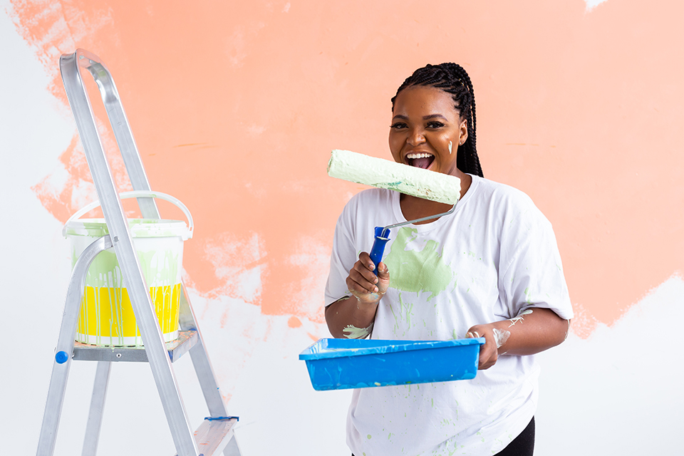 Smiling african american woman painting interior wall of home. Renovation, repair and redecoration concept.