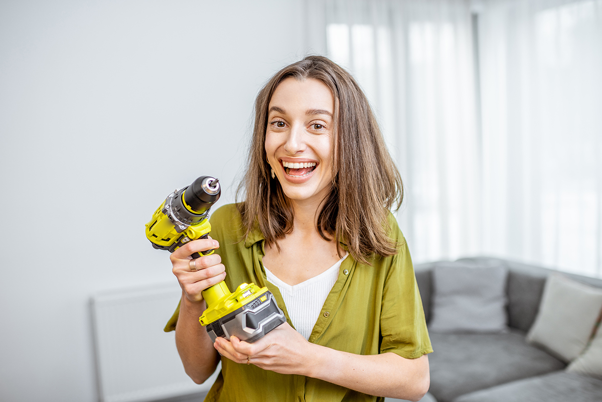 Handywoman with cordless screwdriver at home