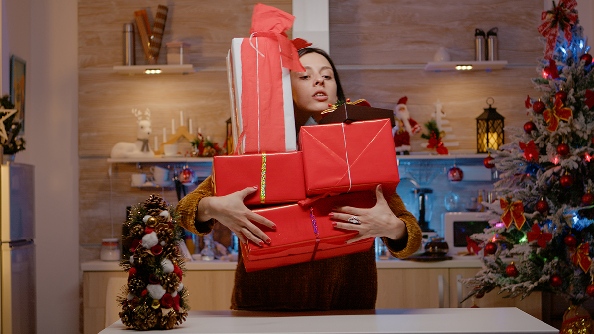 Woman carrying gift boxes feeling stressed about christmas