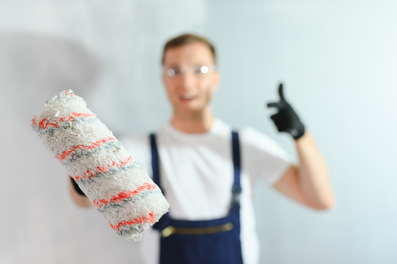 Young worker painting wall in room