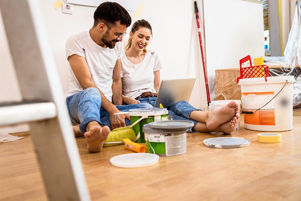 Young couple sitting on the floor choosing color via laptop for