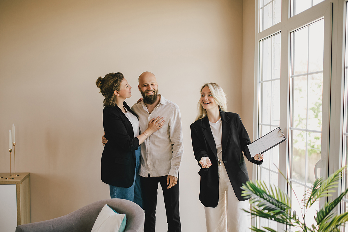 Real estate agent demonstrating a new apartment to a happy coupl
