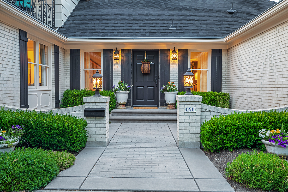 a white brick house with a black door and grey shutters