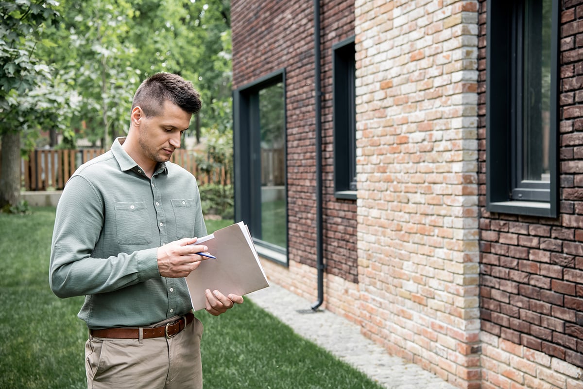 real estate agent holding folder and pen while standing near con