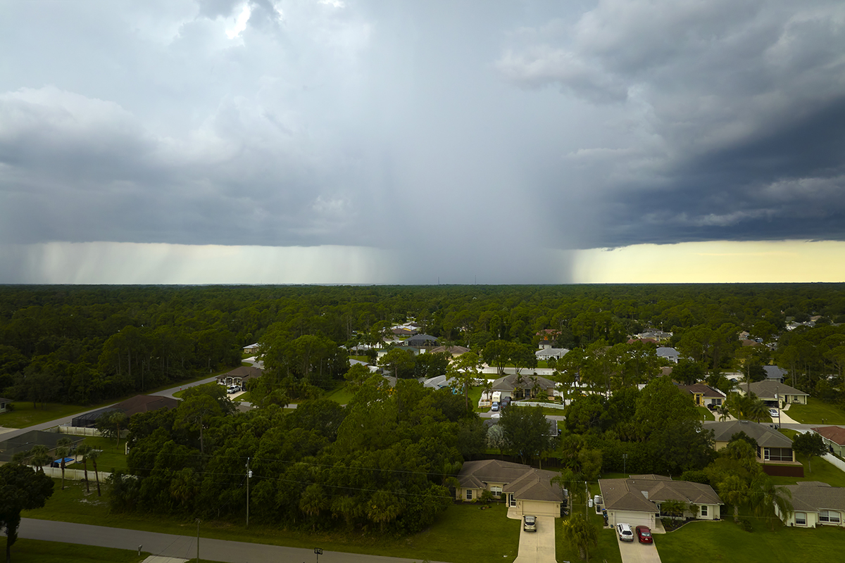 Dark stormy clouds forming on gloomy sky during heavy rainfall season over suburban town area