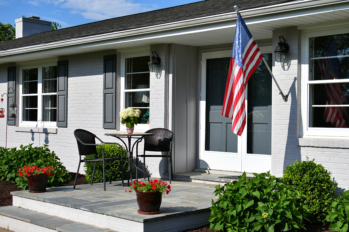 front-porch-of-a-gray-ranch-house-with-an-american-2023-11-27-05-13-19-utc