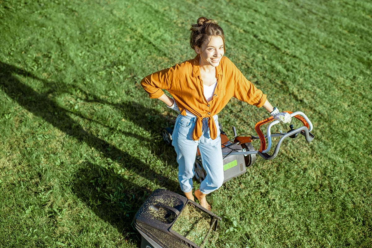 Woman with lawn mower on the backyard