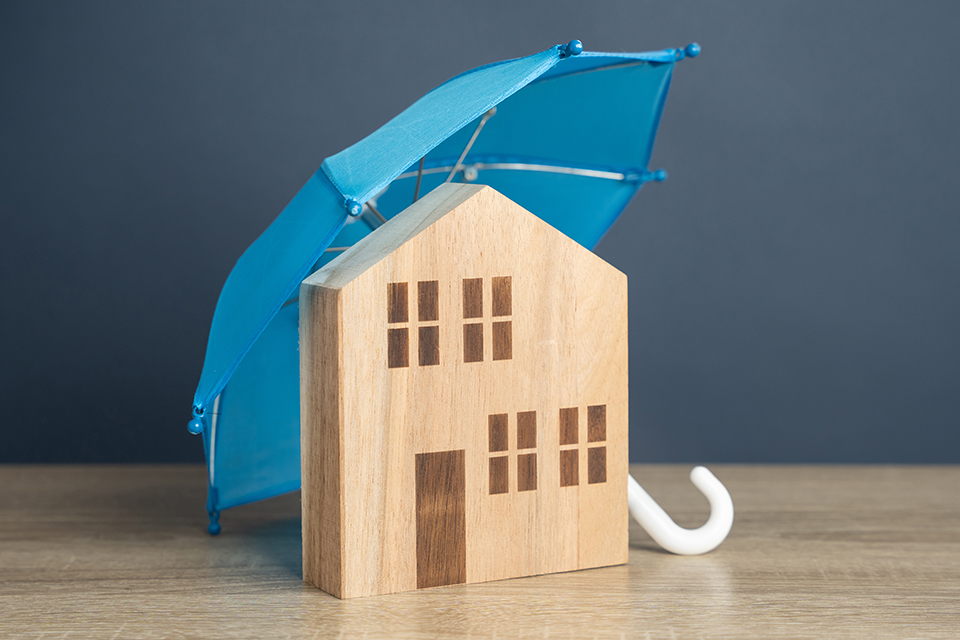 House with blue umbrella. Property insurance. Financial security. Protect investment and be prepared for unforeseen events. Repairs or rebuilding in the event of a covered loss.