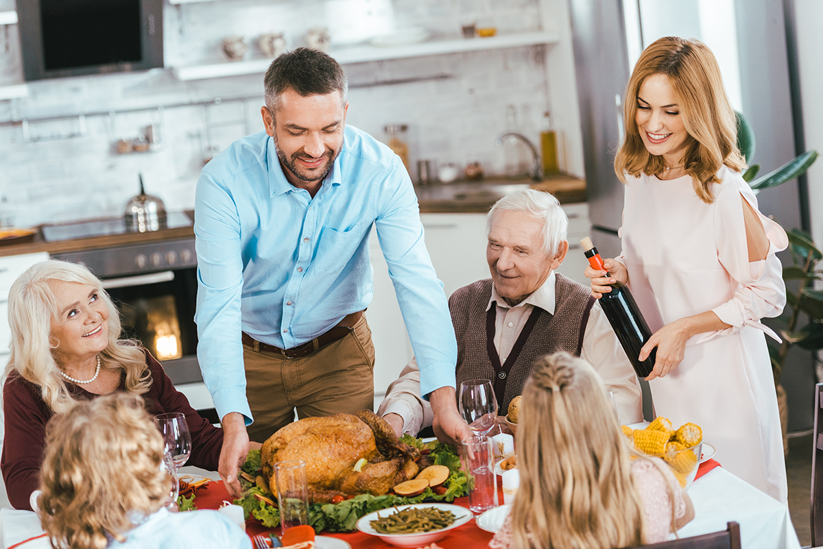 smiling family with turkey celebrating thanksgiving day at home