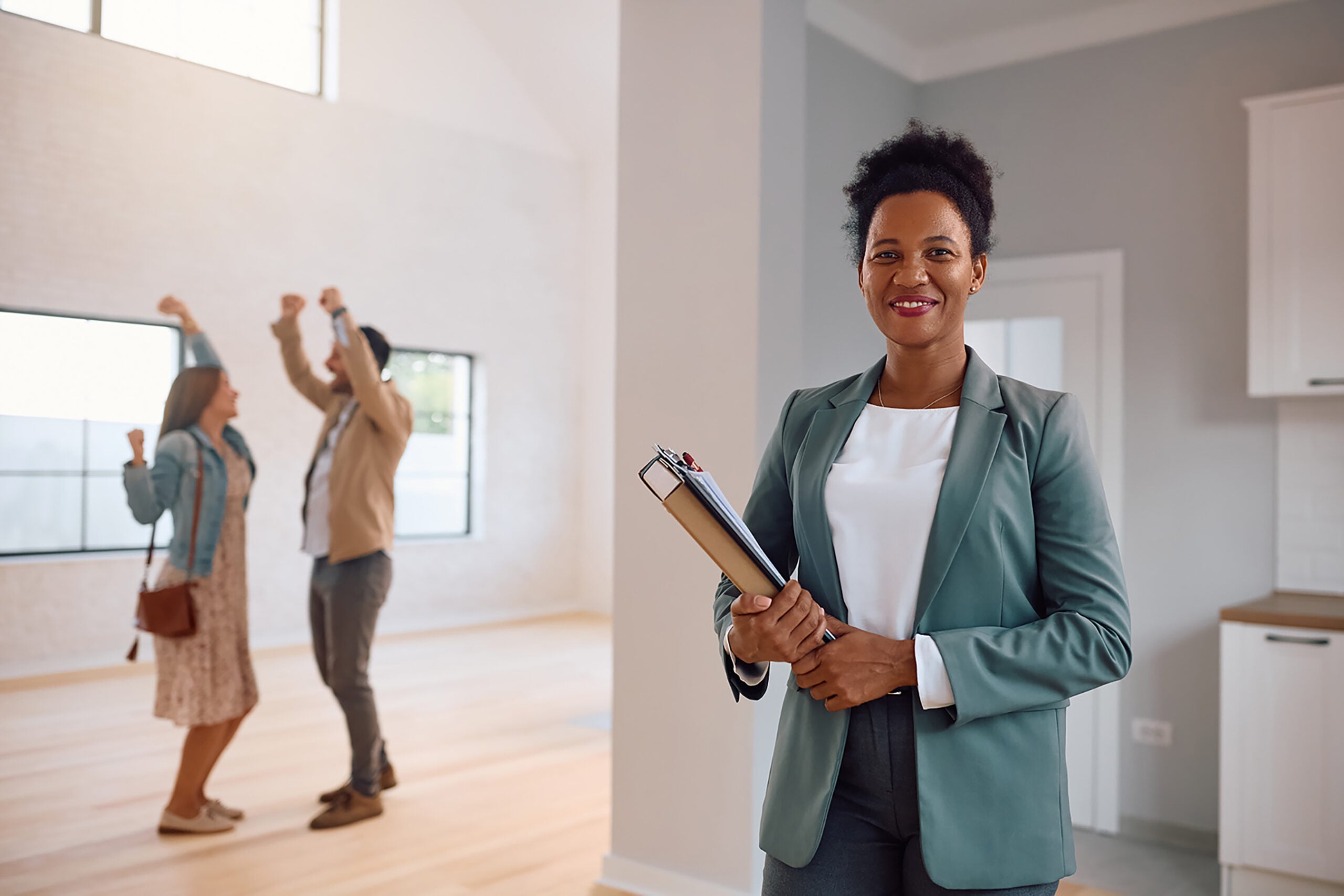 Happy black real estate agent with happy clients in the background.