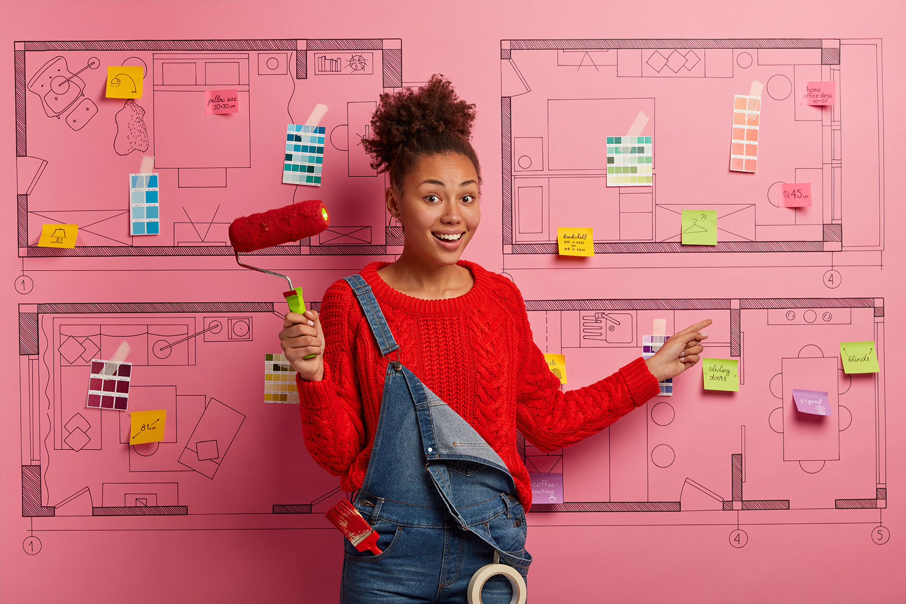Look at this new house sketch! Glad smiling Afro American designer demonstrate her project to renovate apartment, points at sticky notes tells which furniture to buy holds paint roller, building tools