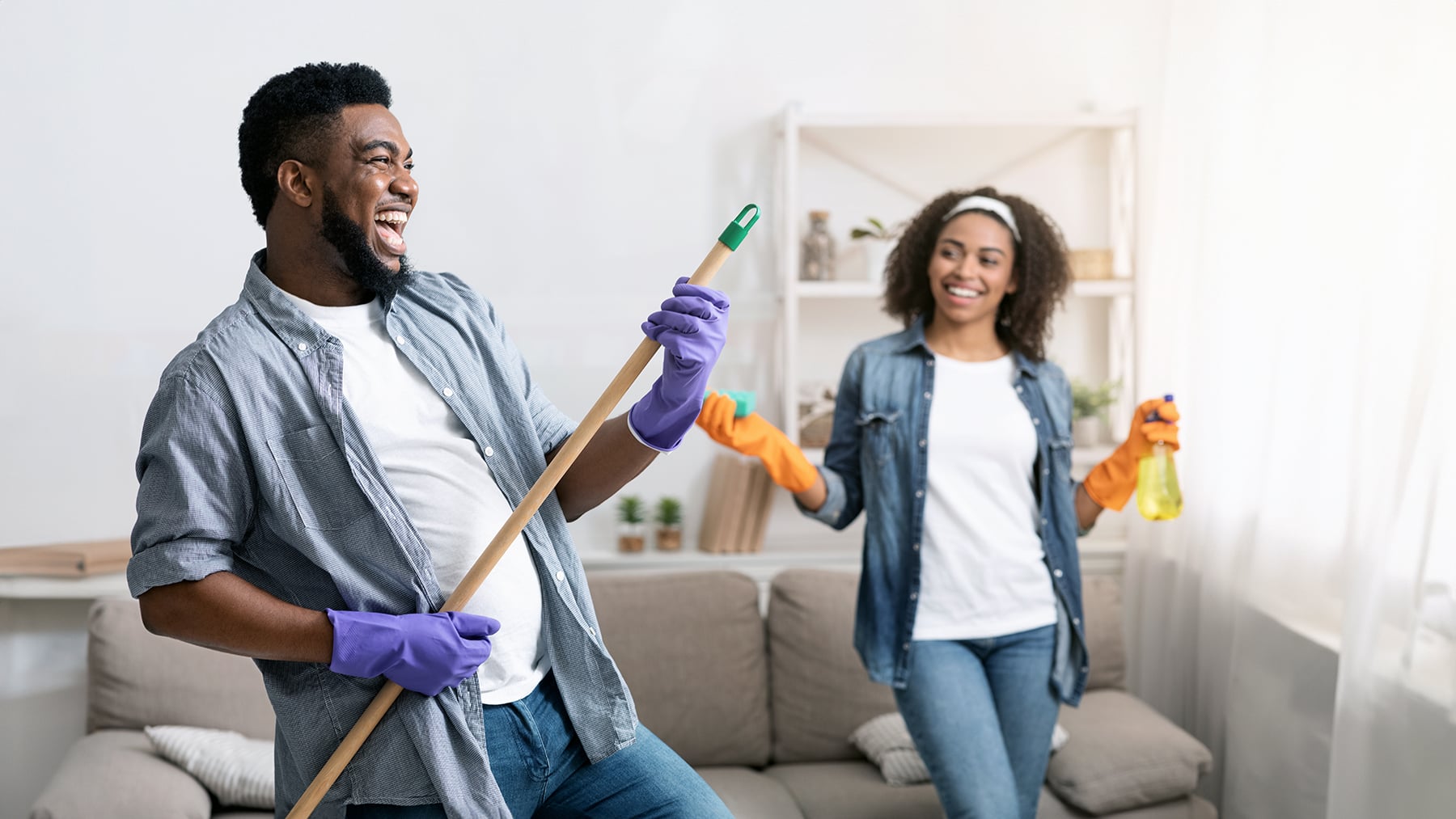 Tidying With Fun. Joyful Black Couple Fooling While Cleaning Flat Together
