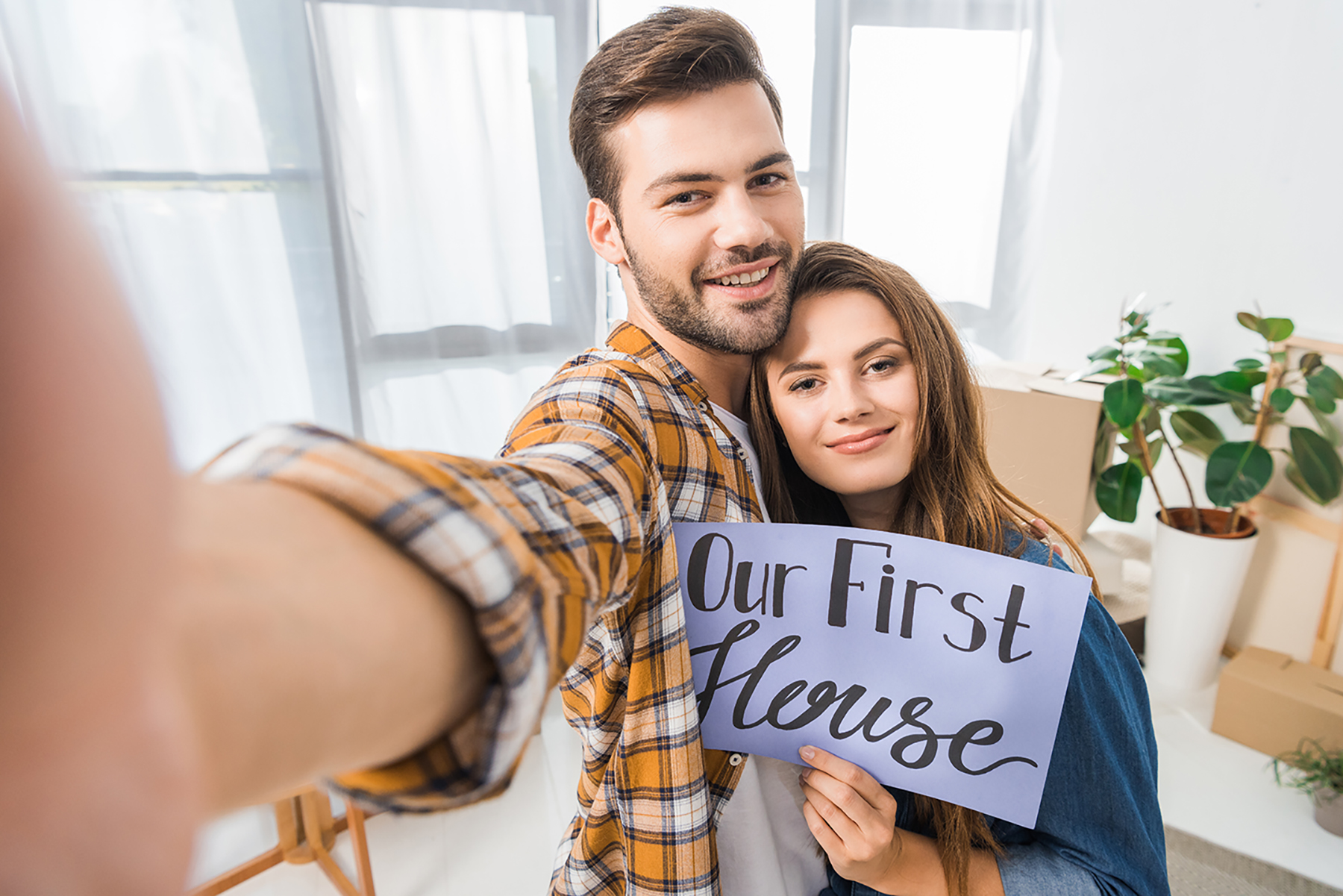 camera point of view of smiling couple with our first house card