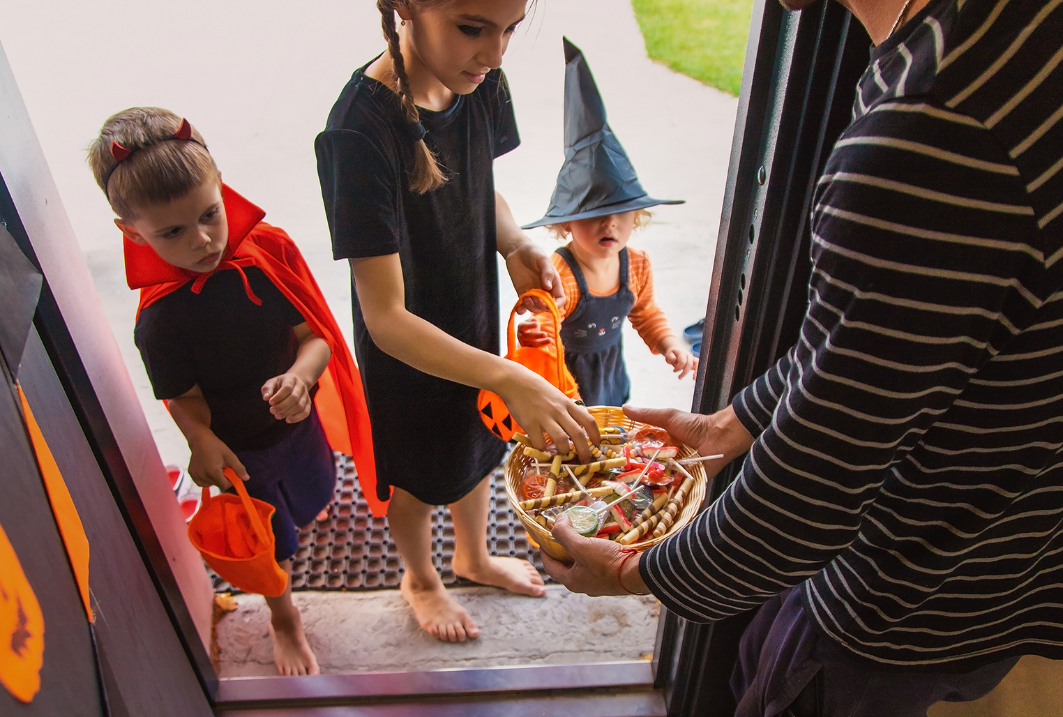 Children take candy from a basket. Halloween.