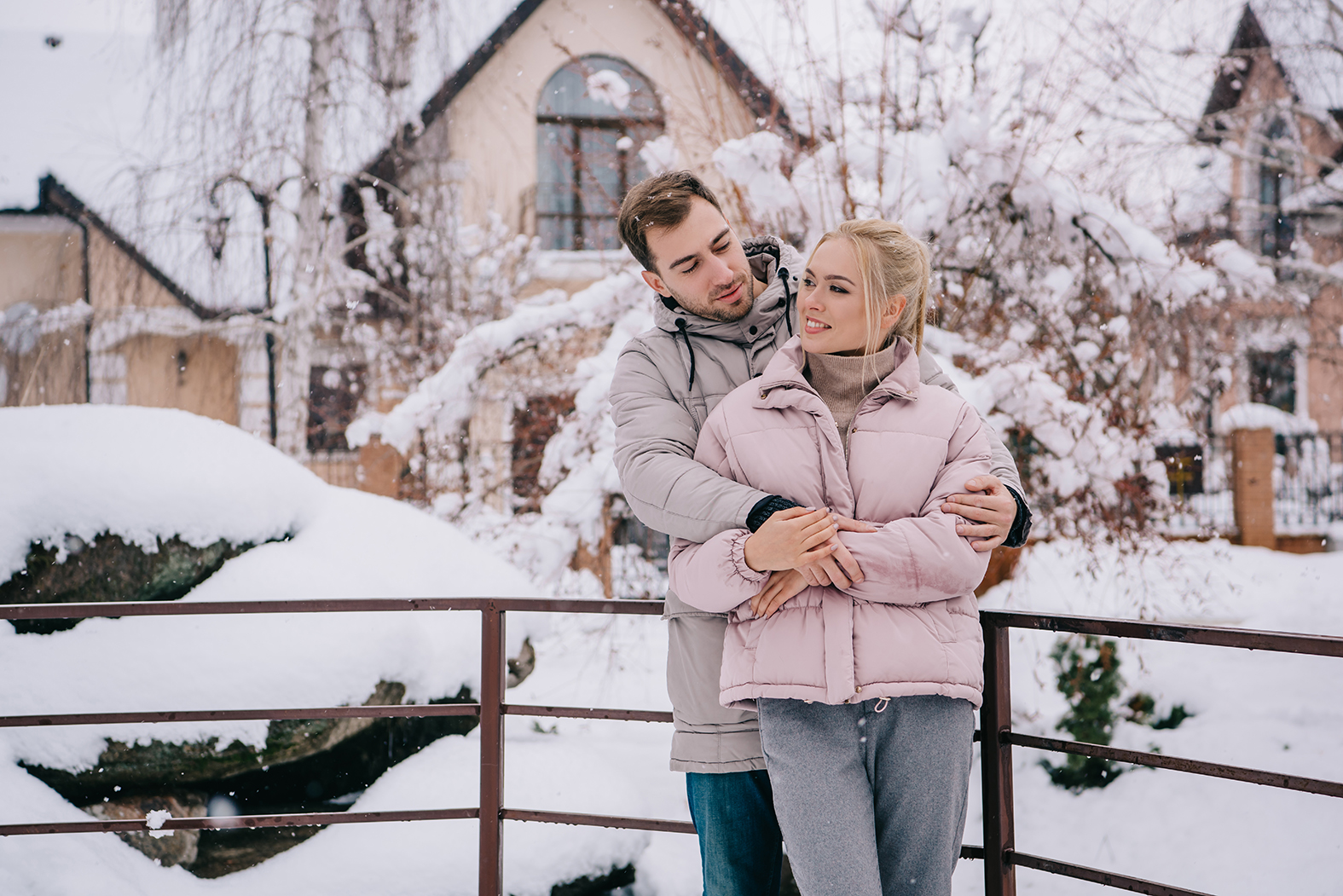 handsome man looking at cheerful girlfriend and hugging in winte