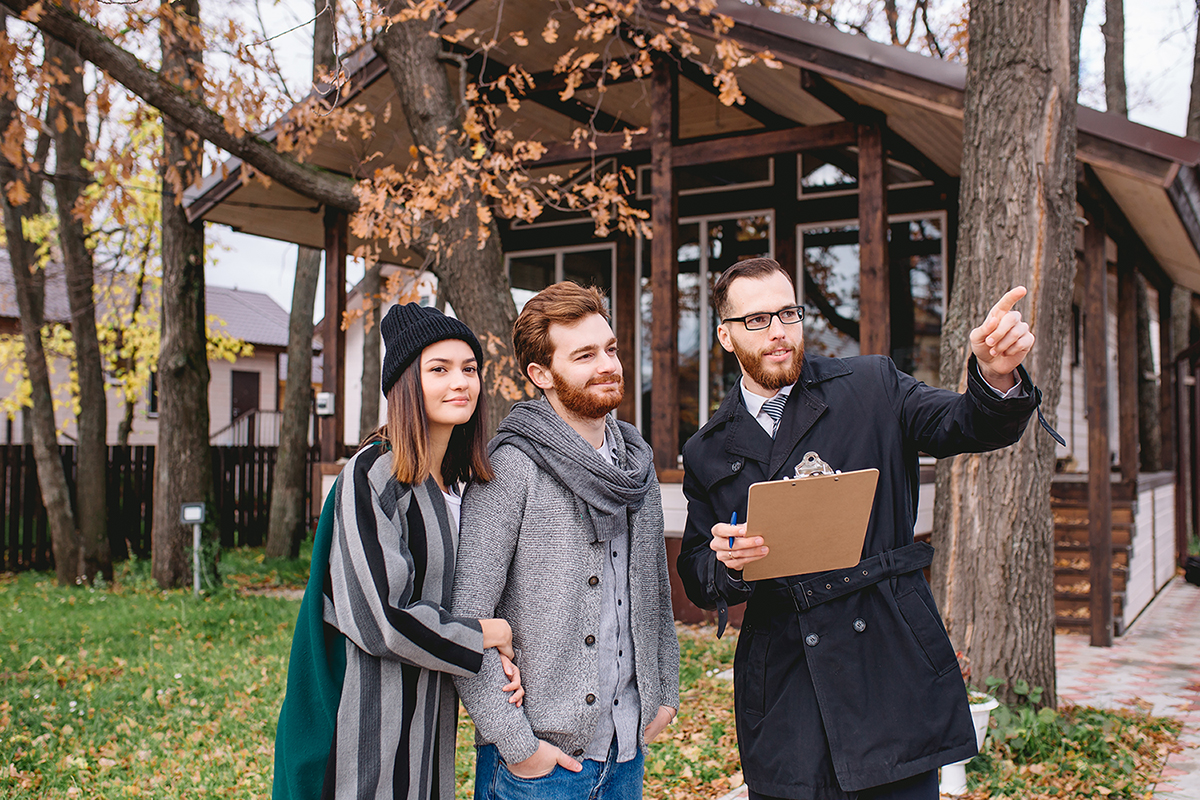 Real-estate agent with young caucasian happy couple buying new house