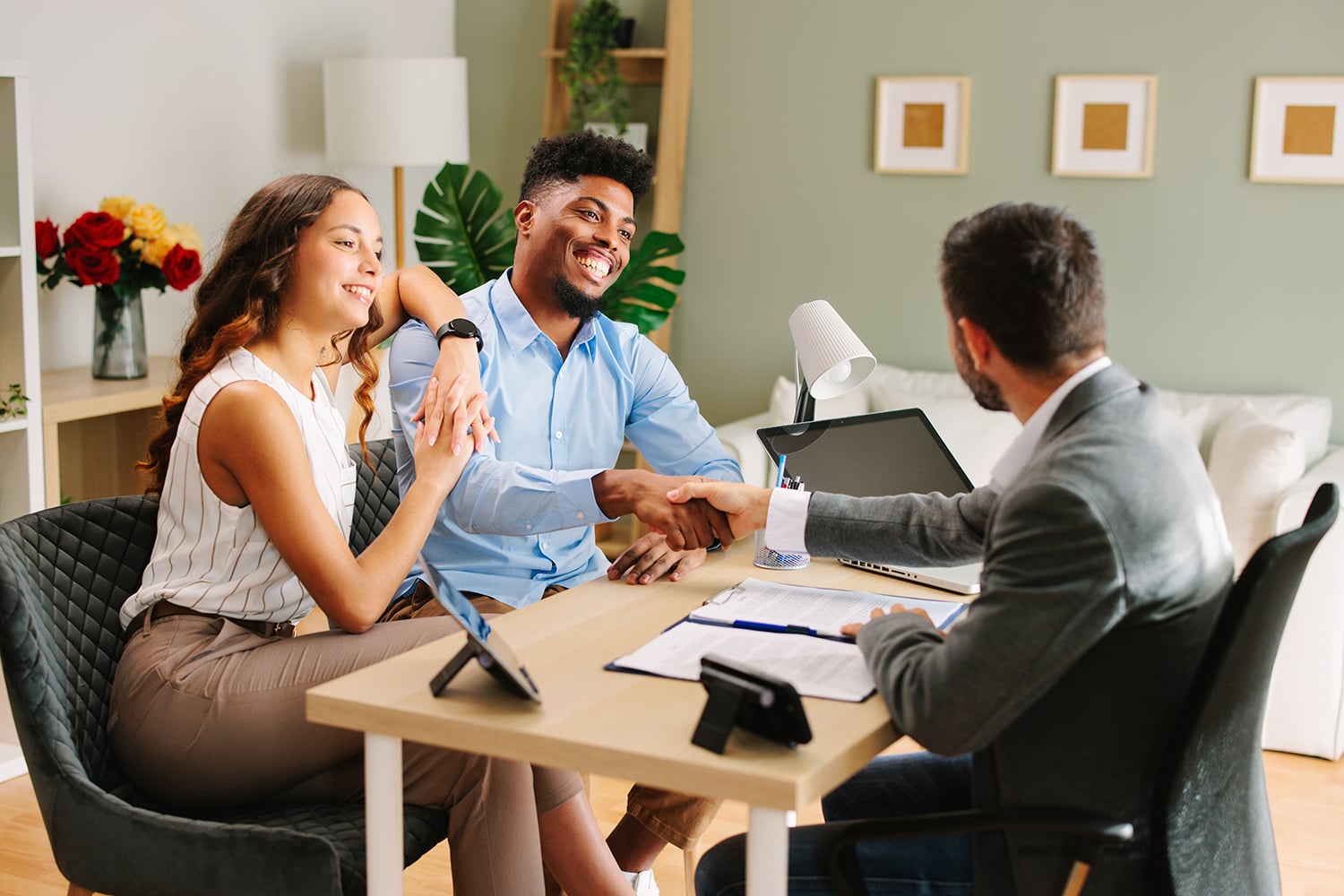 Young Latin American couple makes a deal with an agent in the office and does handshake
