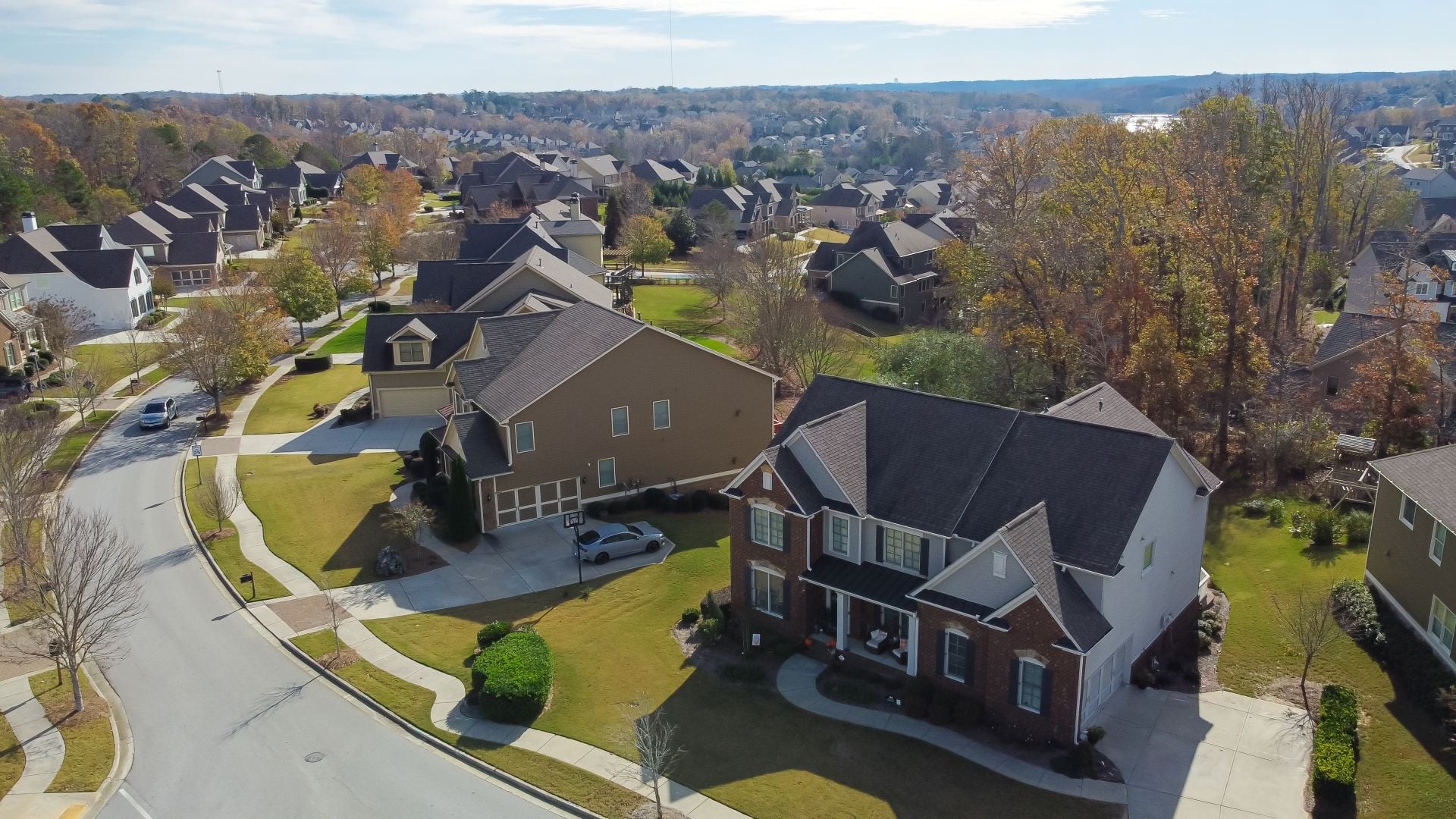 Aerial view suburban residential street with row of upscale two-story new development houses and master planned community in distance background outside Atlanta