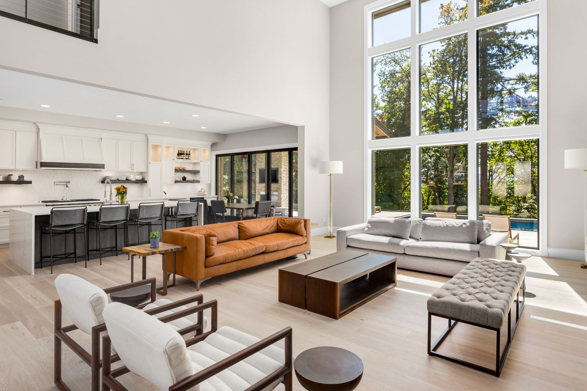 Beautiful Living Room and Kitchen in New Modern Luxury Home. Features Wall of Windows, Floor to Ceiling Fireplace Surround