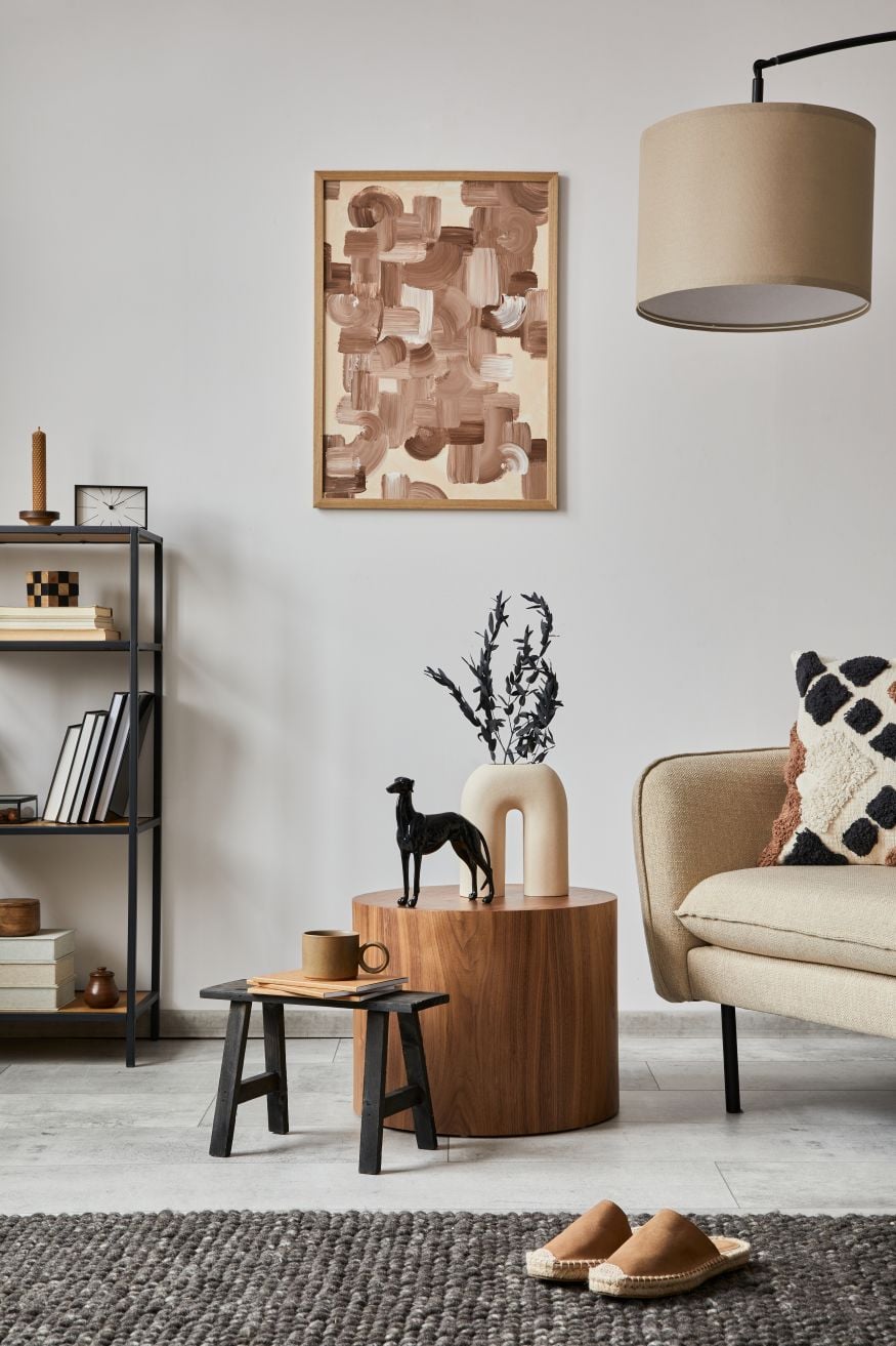 Modern living room interior composition with mock up poster frame, beige sofa, black metal shelf and small home decorations. Creative home staging. White wall. Copy space. Template.