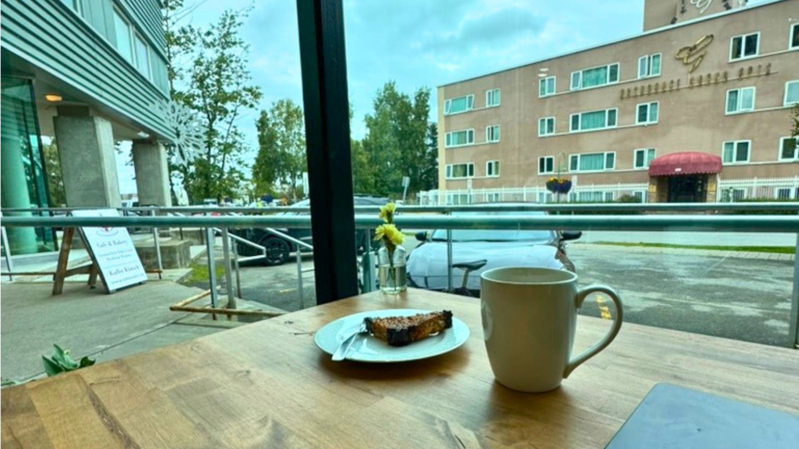 Coffee cup and pastry inside a downtown Anchorage coffee shop with city buildings outside