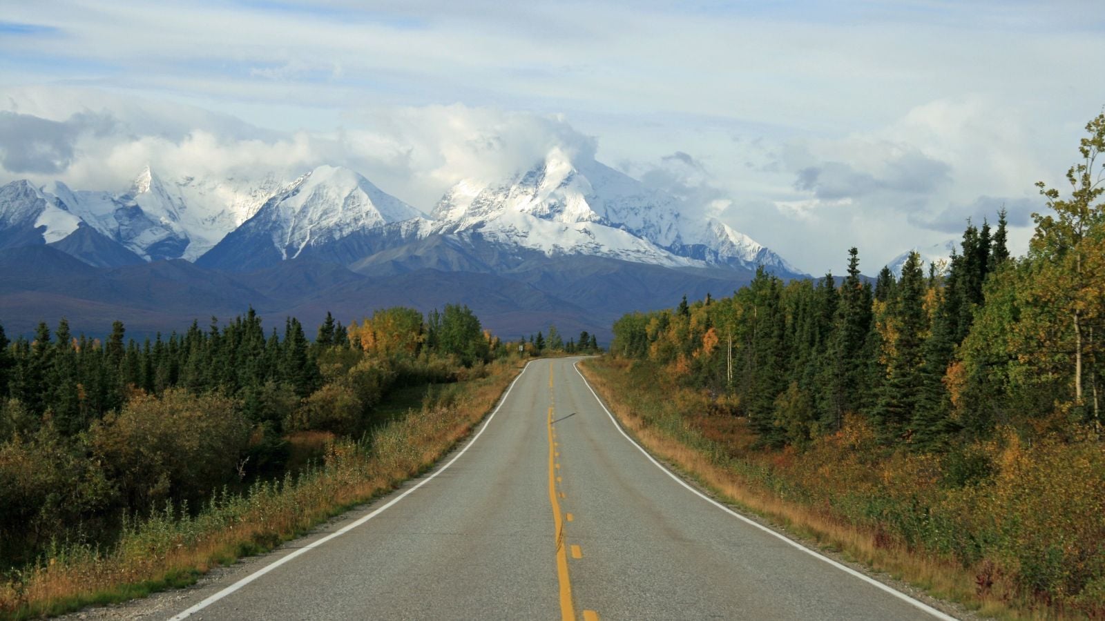 Empty Alaska road leading toward snow covered mountains near Anchorage