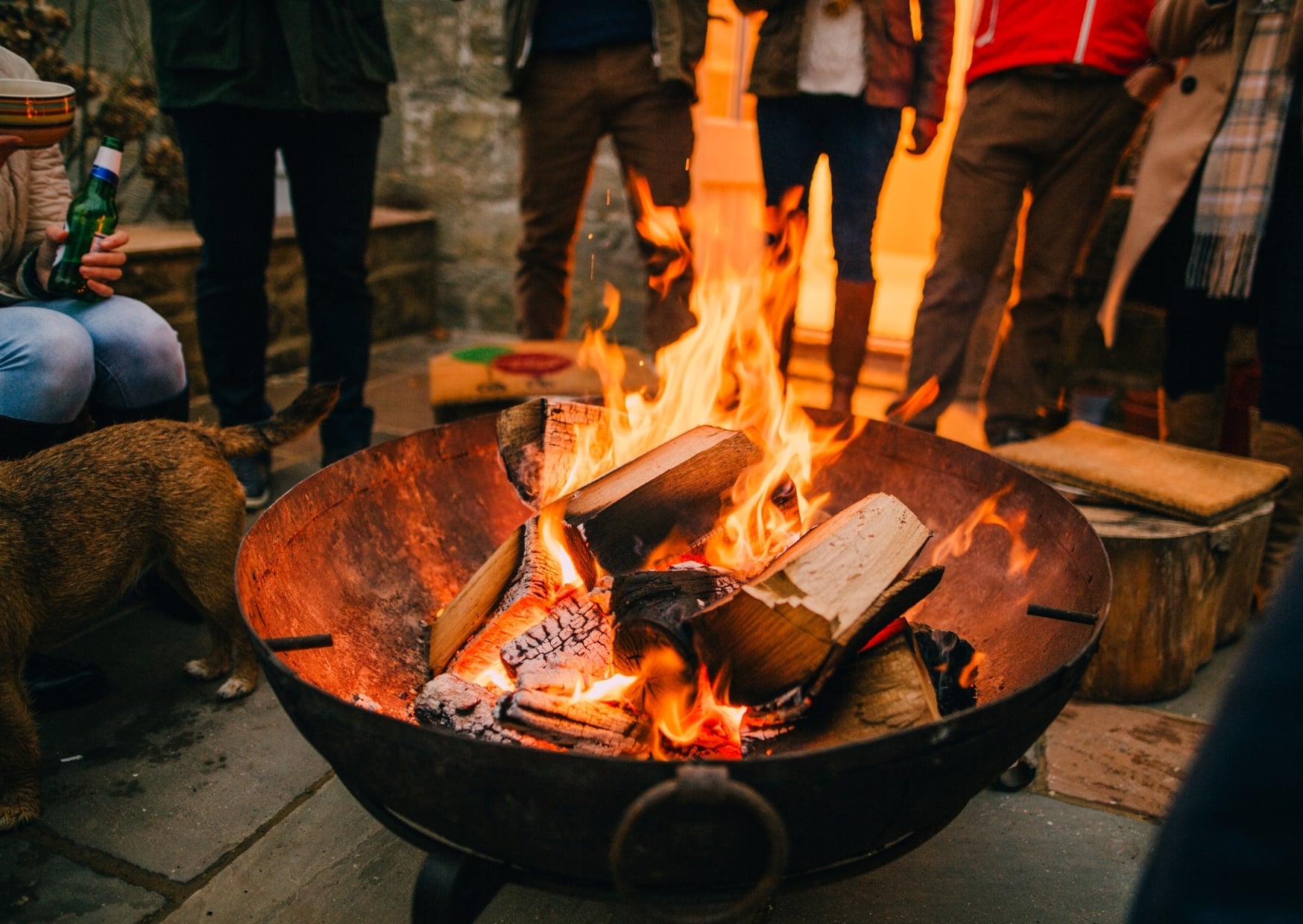 Friends gathered around a wood fire pit in an Anchorage backyard