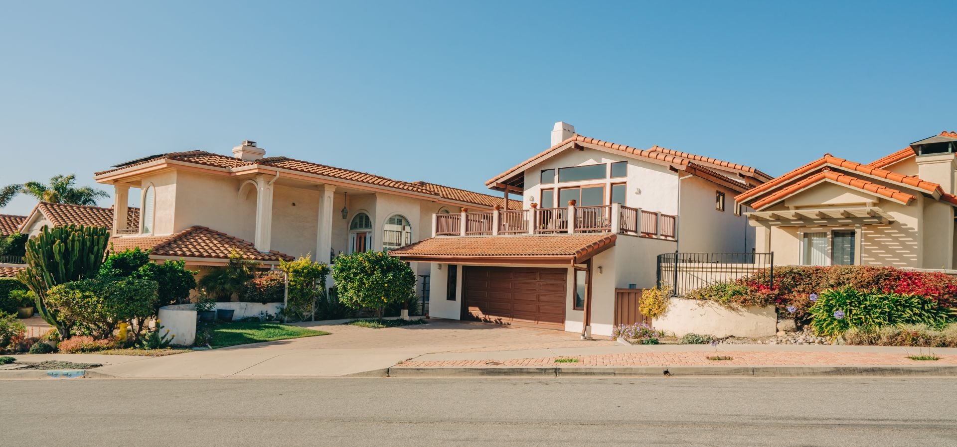 Beautiful houses with nicely landscaped front the yard and clear blue sky on background in a small beach town in California.