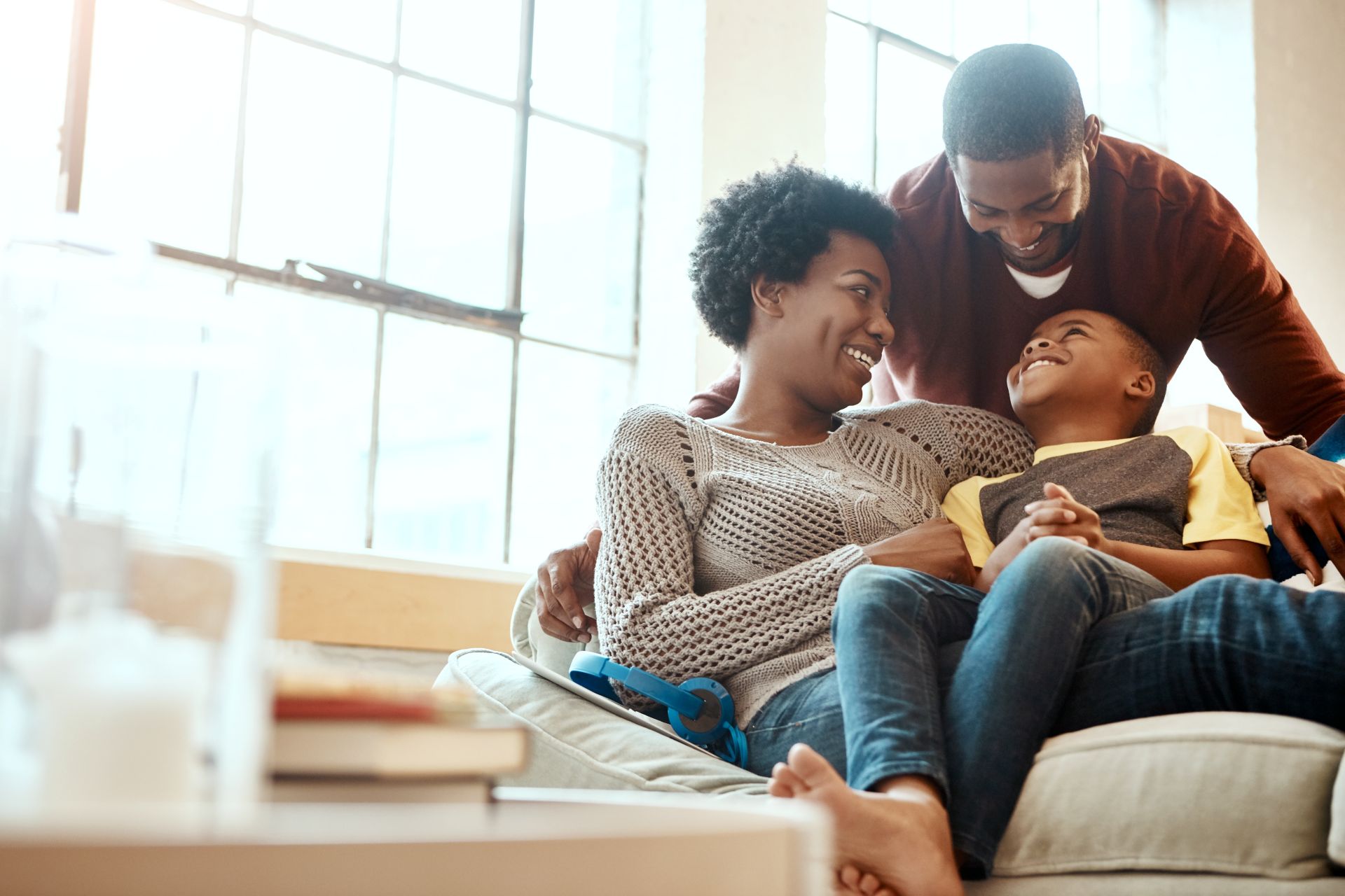 Black family, happy and relax on sofa with boy and parents, hug and laughing in their home together.