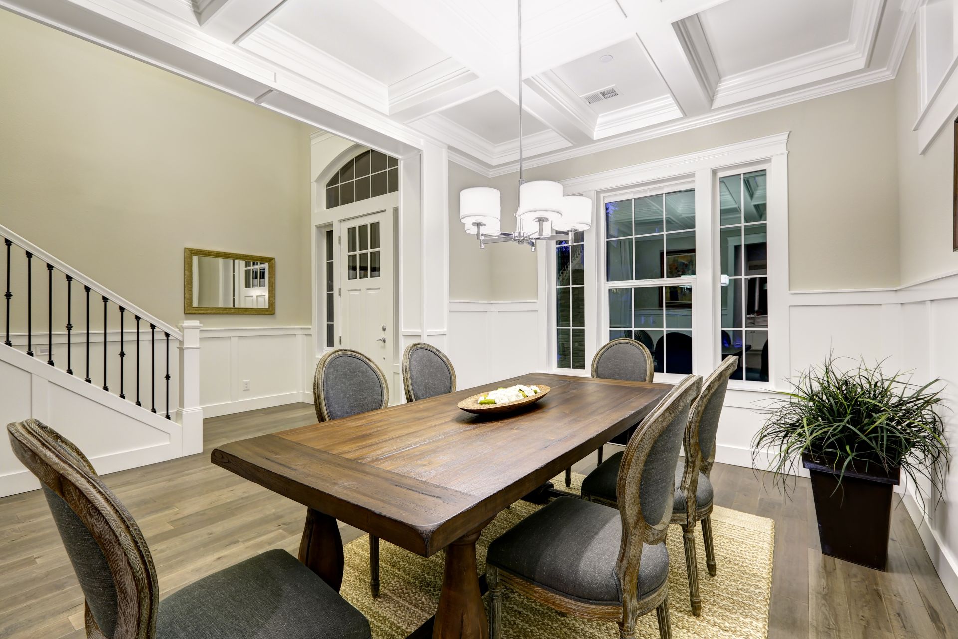 Lovely craftsman style dining room with coffered cealing over wooden dining table surrounded by grey chairs atop sisal rug. Northwest, USA