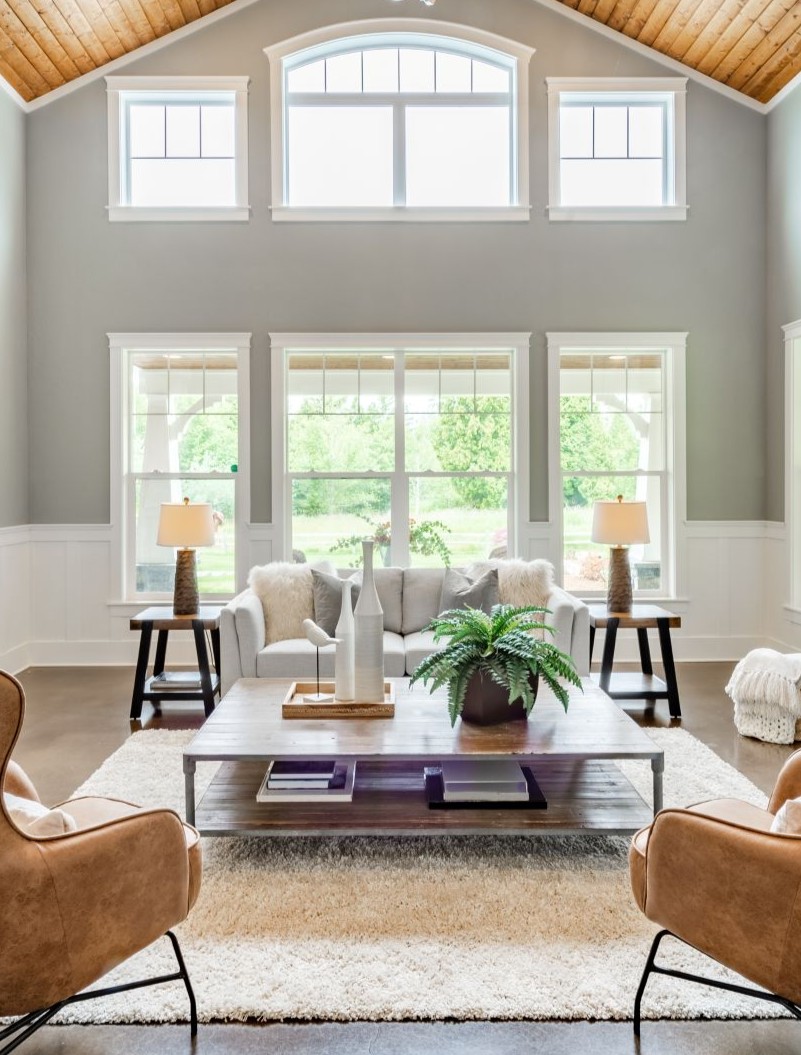 Living room interior with vaulted ceiling with wood cedar panelling stone fireplace brown leather armchairs coffee table and area rug natural brown tones (2vertical)