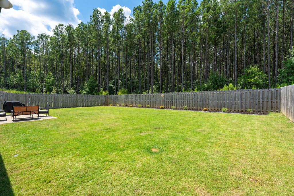 Fenced backyard backing to a mature pine tree line in Chelsea, Alabama