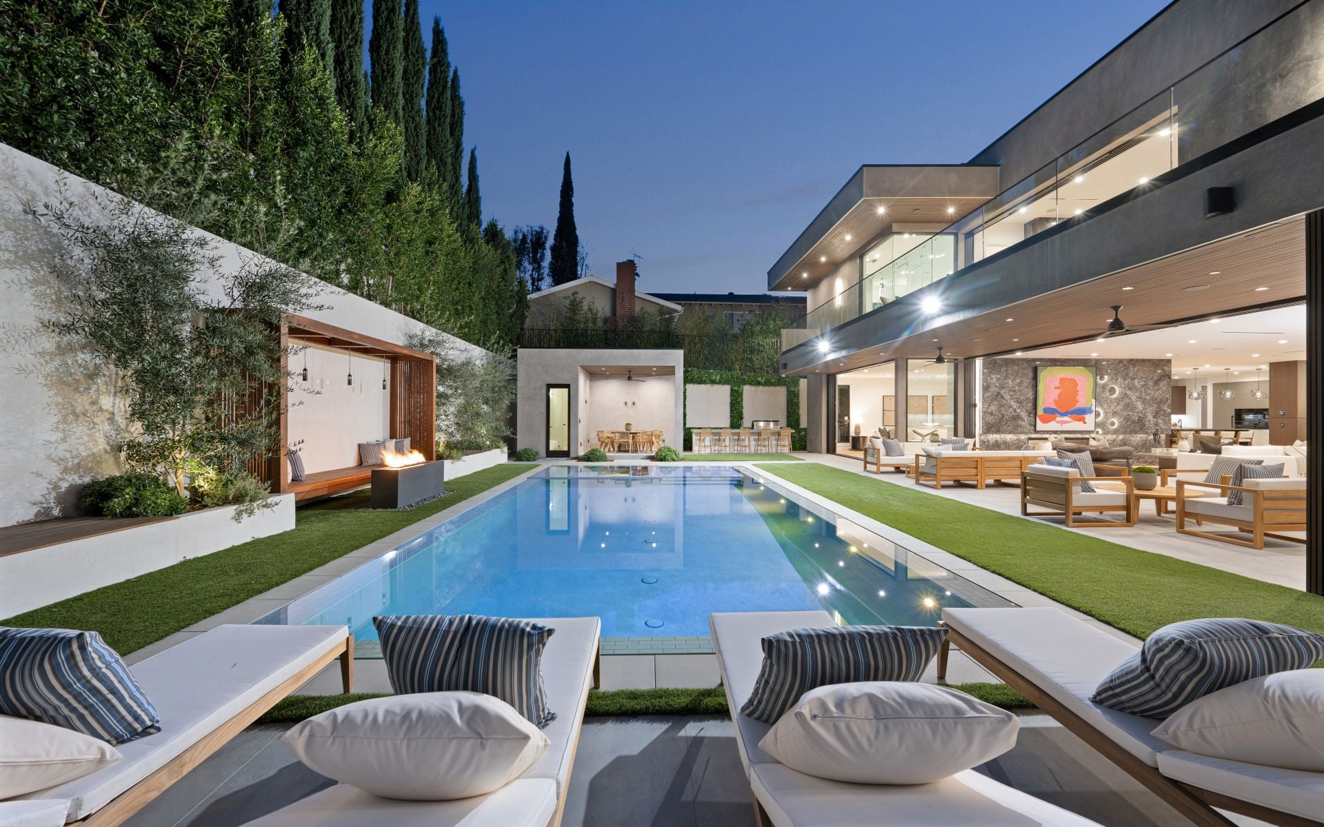 An Indoor pool surrounded by lush greenery, adorned with comfortable chairs and a table,
