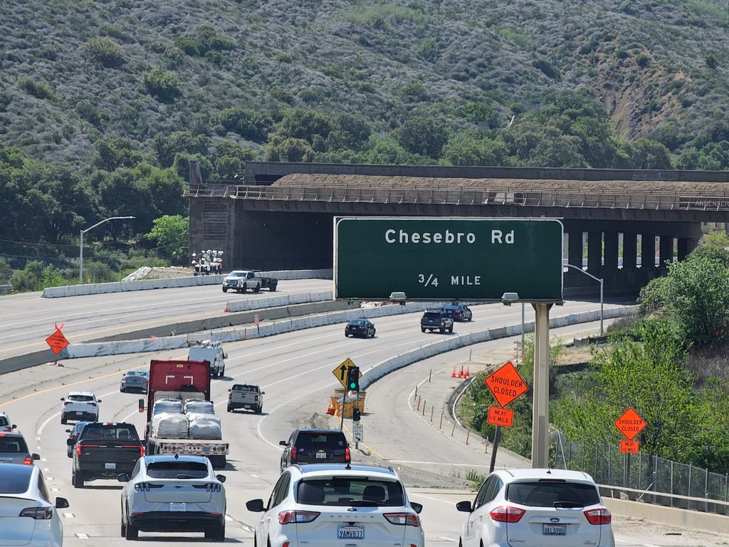 The Chesebro Road exit sign on US 101 with the Wallis Annenberg Wildlife Crossing behind it, April 2025