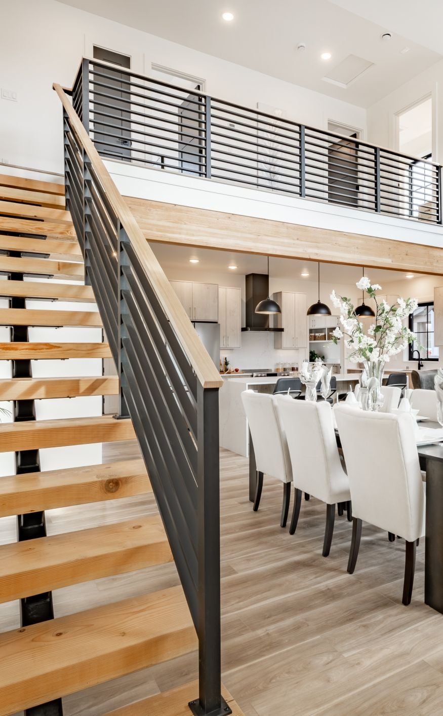 Kitchen and dining room interior with light colors of aqua blue turquoise large exposed staircase with wrought iron hardwood floors
