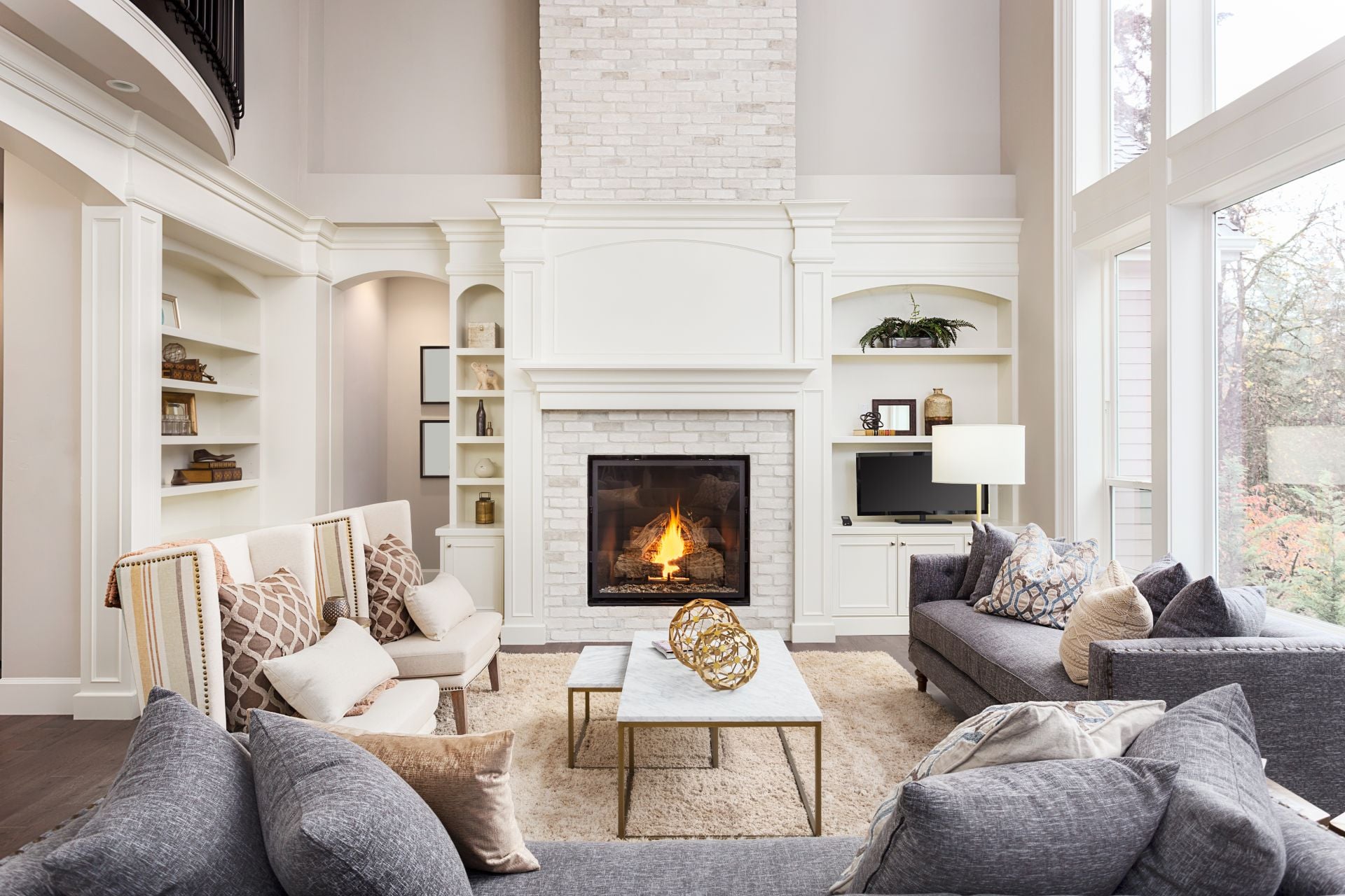 Beautiful living room interior with hardwood floors and fireplace in new luxury home. Large bank of windows hints at exterior view