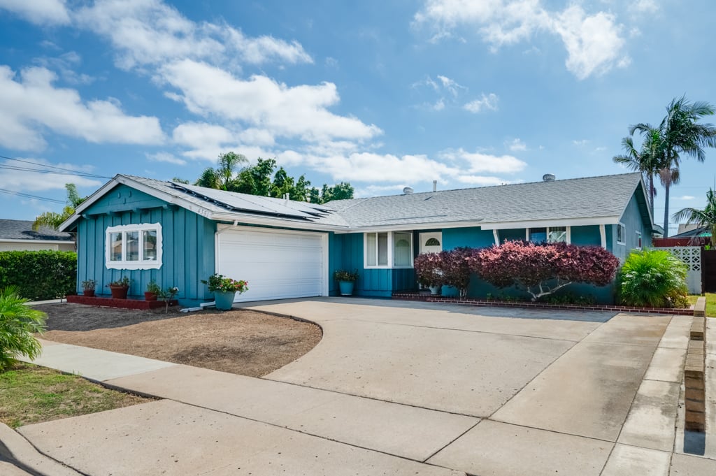 Blue single-story ranch home in Clairemont, San Diego, with a two-car garage, solar panels on the roof and a wide driveway