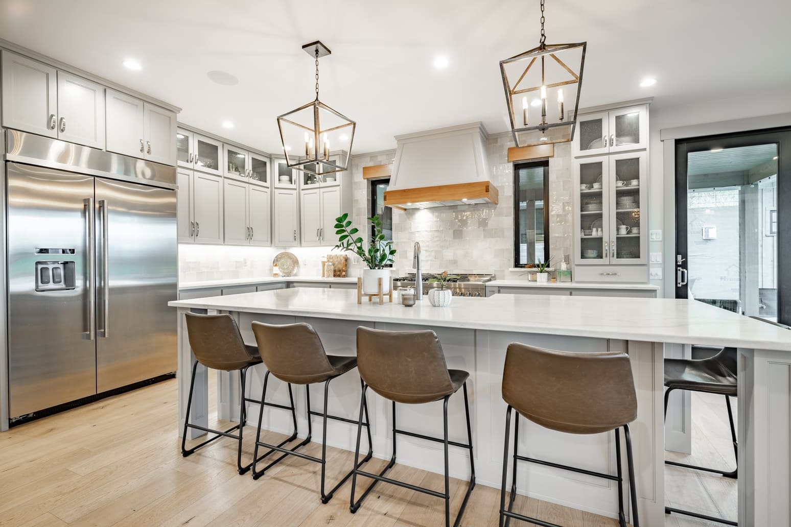 Interior modern farmhouse kitchen and dining room with white countertops bar stools large dining table stainless appliances and view to living room with vaulted ceiling