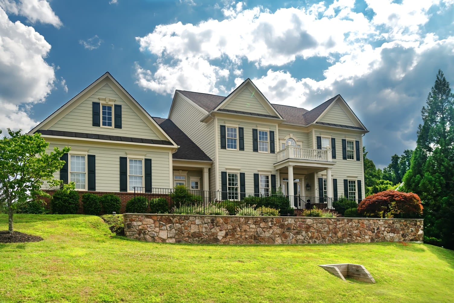 Luxury country home with large green lawn and landscaping in front yard.